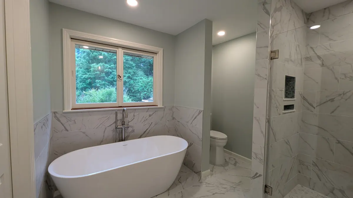 Bathroom with freestanding tub, marble-look tile and glass shower