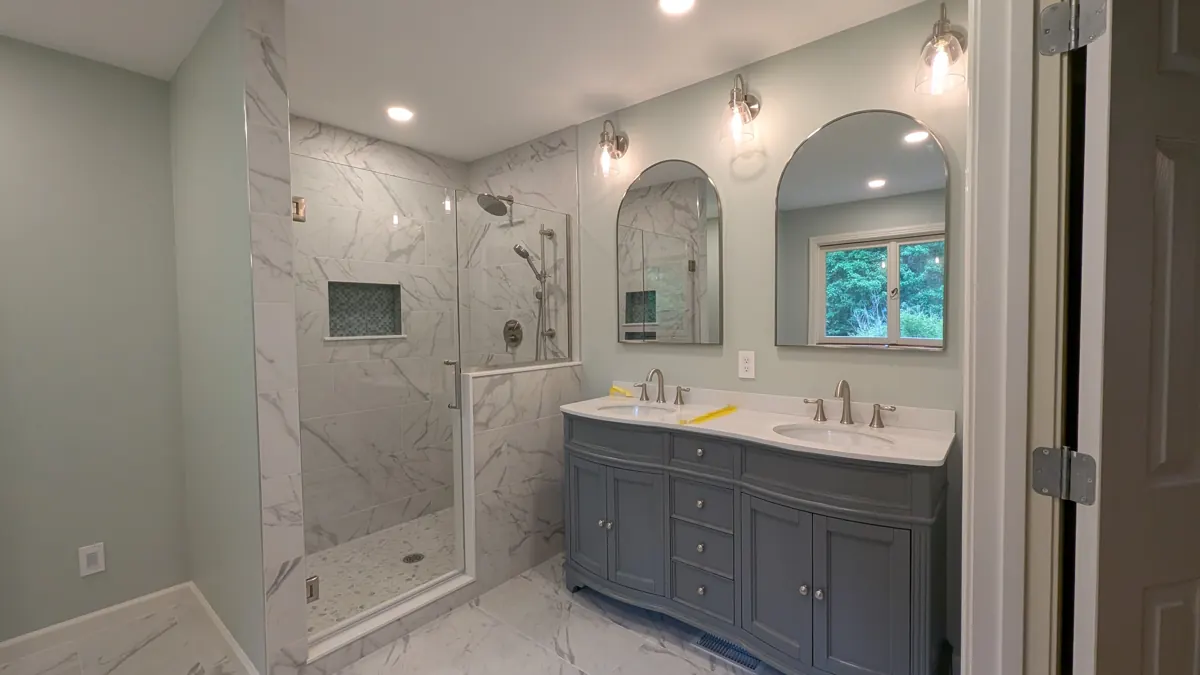 Bathroom with double vanity, arched mirrors and tiled shower