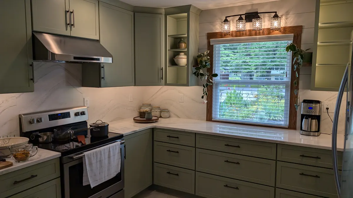 Sage green kitchen with quartz counters and full-height backsplash
