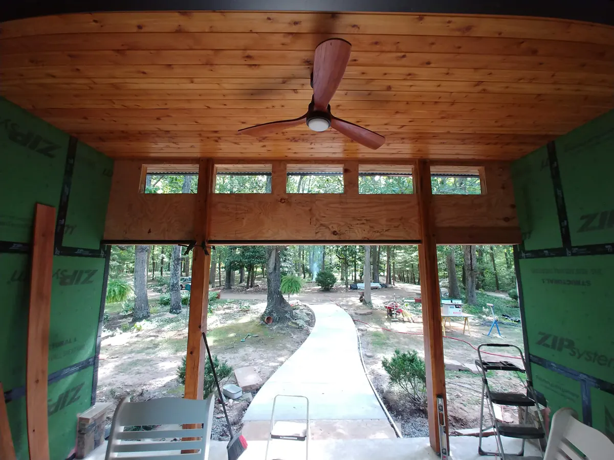 Covered porch with wood plank ceiling and clerestory windows under construction