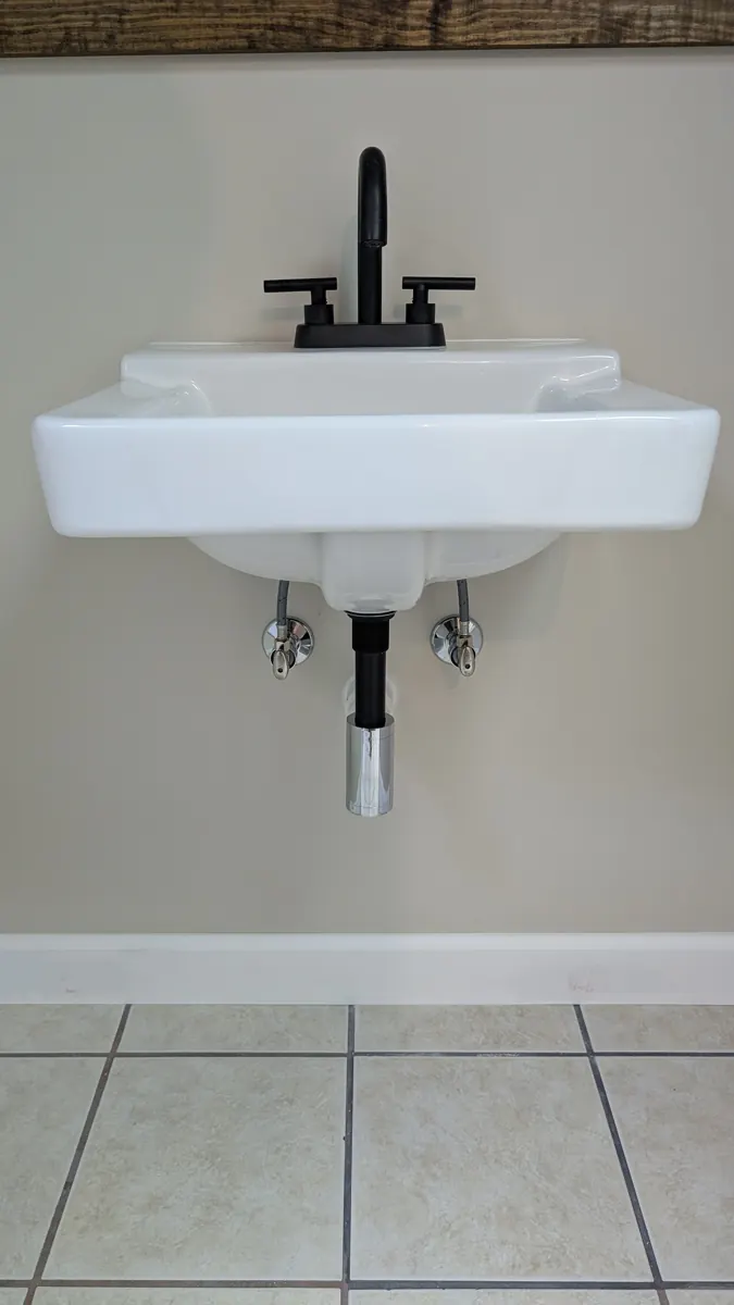 Wall-mounted white sink with matte black faucet